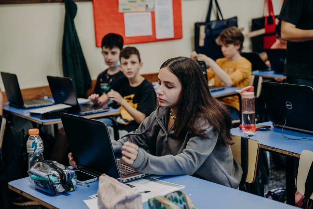 Adolescentes en salón de clase con computadoras personales