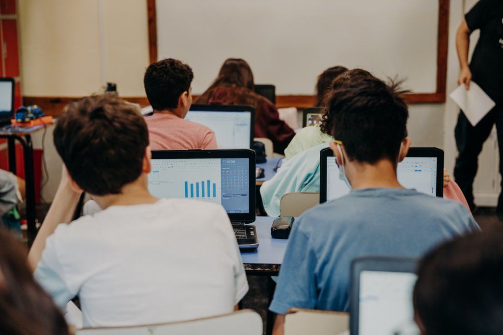 Adolescentes en salón de clase con computadoras personales