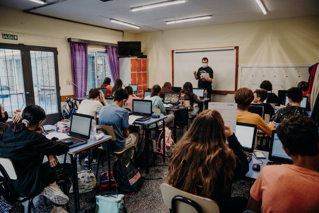 Adolescentes en salón de clase con computadoras personales