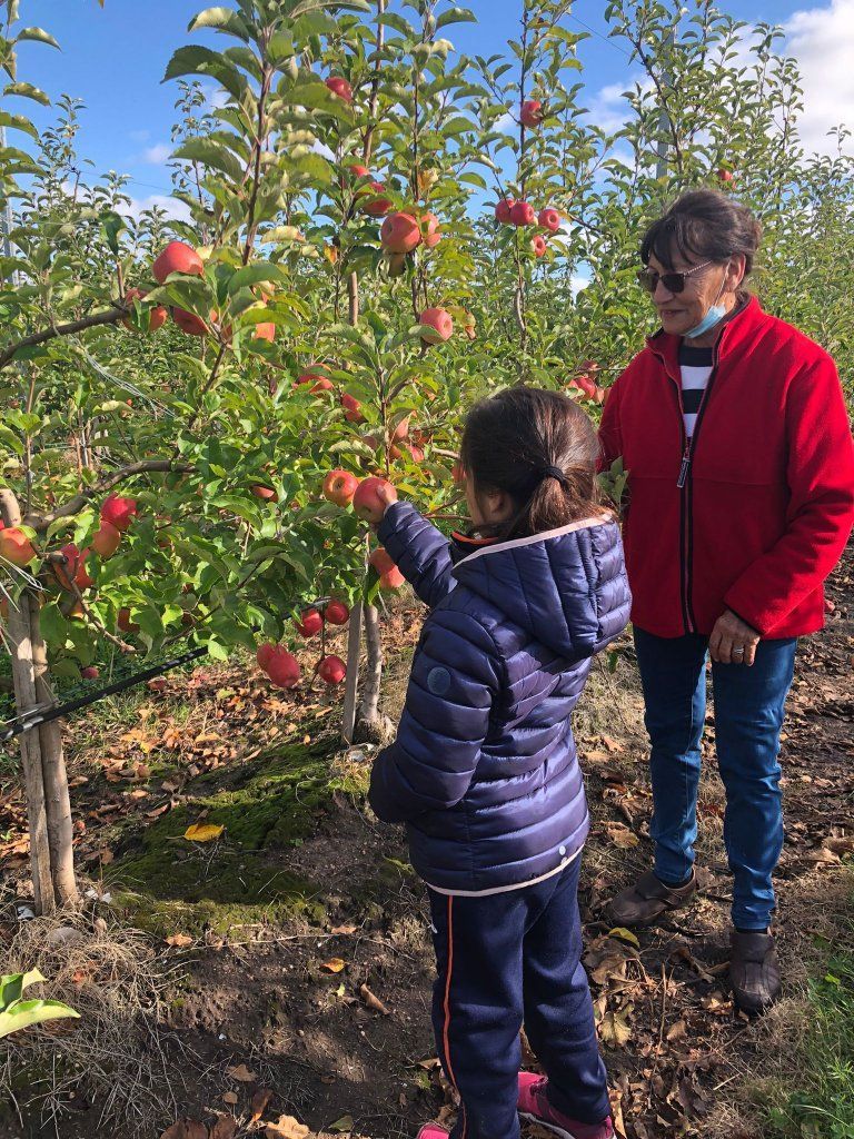 Niña sosteniendo una manzana junto a una adulta