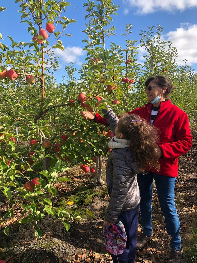 Niña sosteniendo una manzana junto a una adulta
